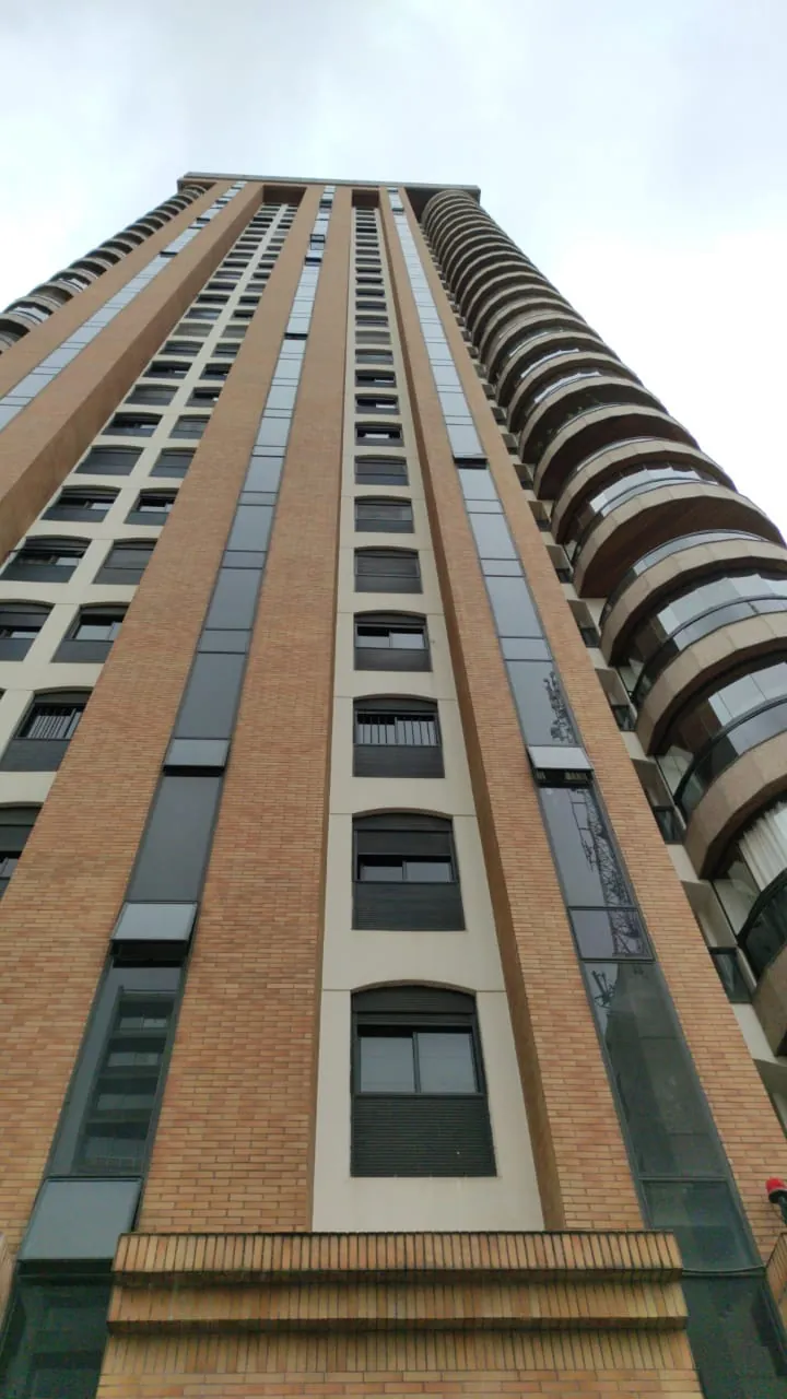 Torre residencial vista de baixo, com fachada em tijolo e varandas